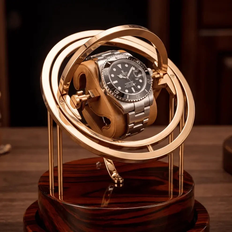 Gold Astronome Prestige watch winder with rotating metal structure and dark wood base for one automatic watch.