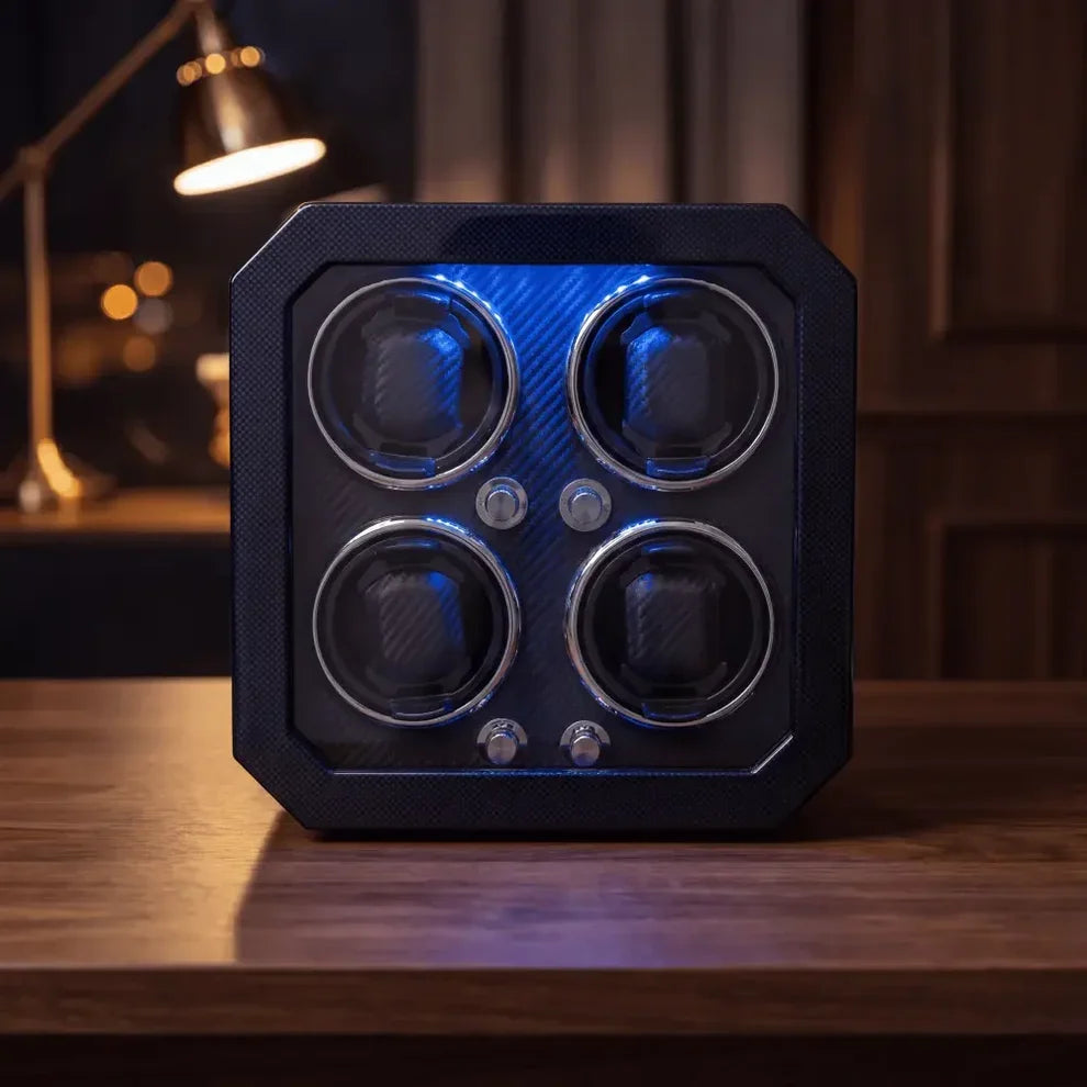 Black carbon fibre watch winder for 4 watches with blue LED lighting, a modern and elegant design on a wooden table.