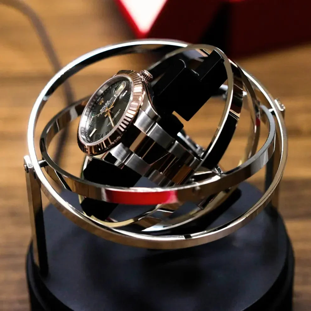 Astronome silver automatic watch winder in stainless steel with rotating gyroscopic design on a black base.
