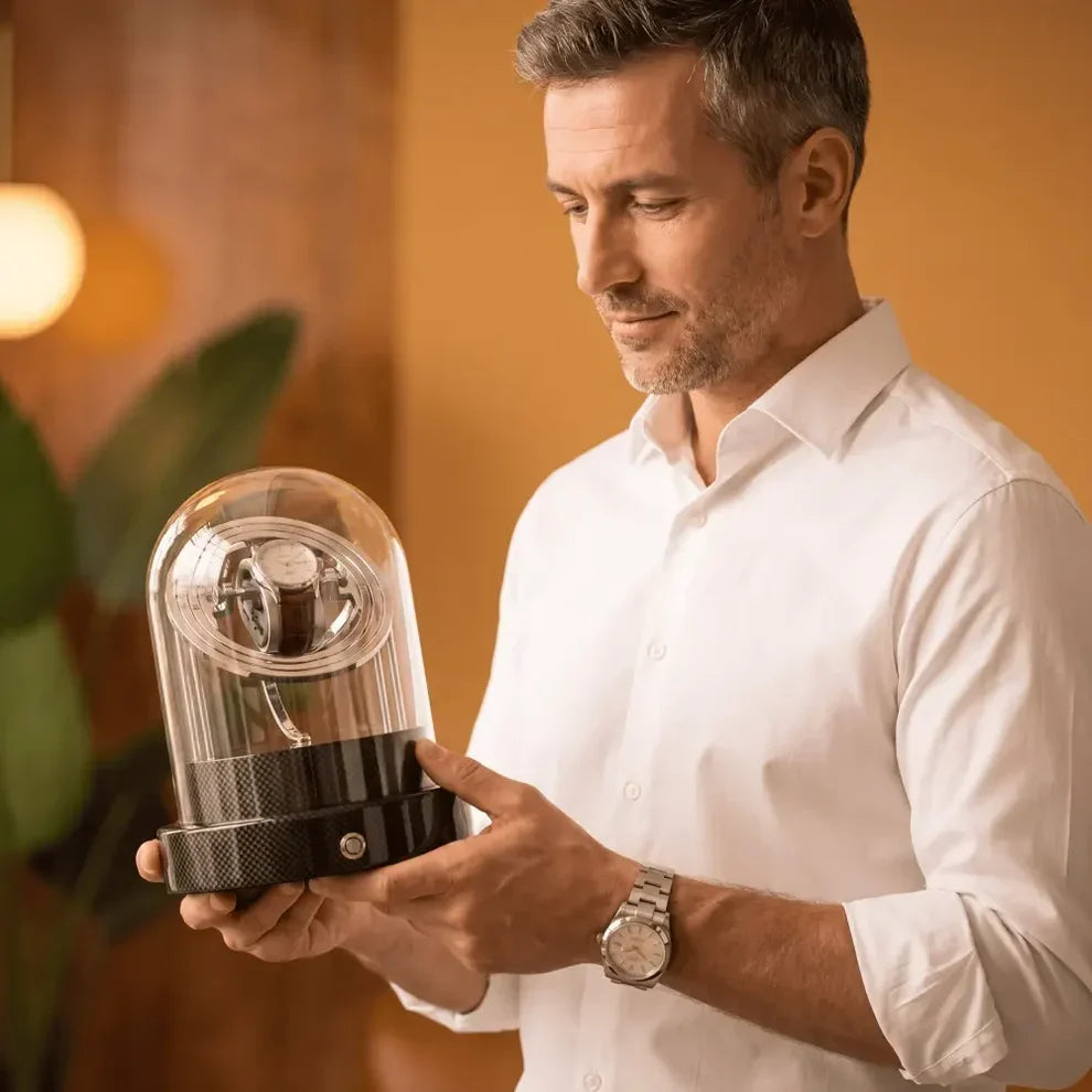 Black Astronome Comète watch winder in carbon fibre with glass dome, holding an automatic watch in an elegant interior.