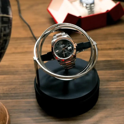 Astronome gold automatic winder in steel with modern circular design for one watch on a black base.