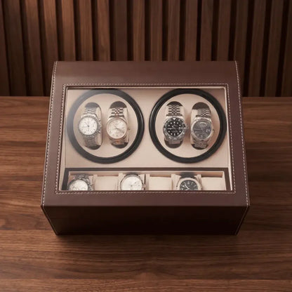 Brown leather watch winder with 4 automatic rotors, 6 storage slots and glass lid on a wooden background.