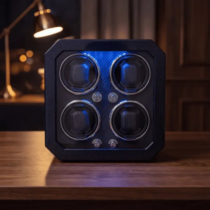 Black carbon fibre watch winder for 4 watches with blue LED lighting, a modern and elegant design on a wooden table.
