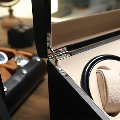 Black leather winder box with beige suede interior, metal hinges and glass lid for watches.