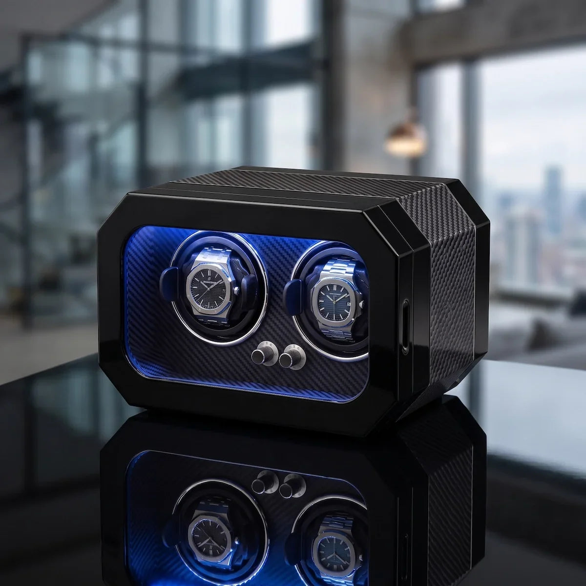 Black carbon fibre watch winder for 2 watches with blue LED lighting and a silent motor on a reflective surface.